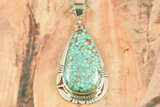 Genuine High Grade Kingman Web Turquoise set in Sterling Silver Pendant. Created by Navajo Artist Phillip Sanchez. Signed by the artist. The Mineral Park Mine, in the Cerbat Mountains 14 miles northwest of Kingman, was first mined by Indians centuries before white man came to the area. It is one of the three sites of prehistoric mining localities in the state of Arizona. Mineral Park was the most extensively worked area by the Indians of the three. S.A. �Chuck� Colbaugh found a cache of stone hammers uncovered in ancient trenches and tunnels, when he had the turquoise mining concession in May of 1962. Ithaca Peak and Turquoise Mine (formally called Aztec Mountain or Aztec Peak) are the most famous of the peaks in the area containing turquoise. Free 18" Sterling Silver Chain with purchase of pendant.
